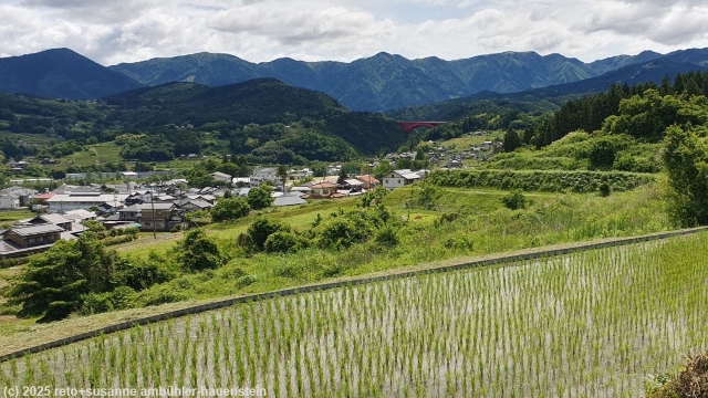 blick vom nakasendo ins tal des kiso river mit der markanten roten ochiaigawabashi im hintergrund